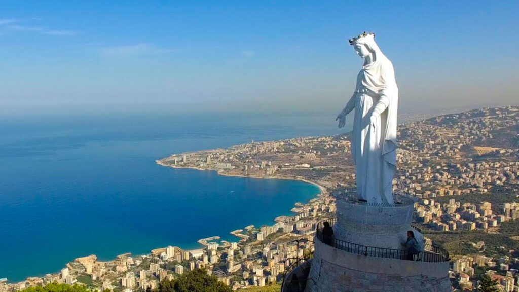 A panoramic photograph immortalizes the iconic "Lady of Lebanon" statue, in the picturesque village of Harissa, overlooking the vast expanse of the Mediterranean Sea.