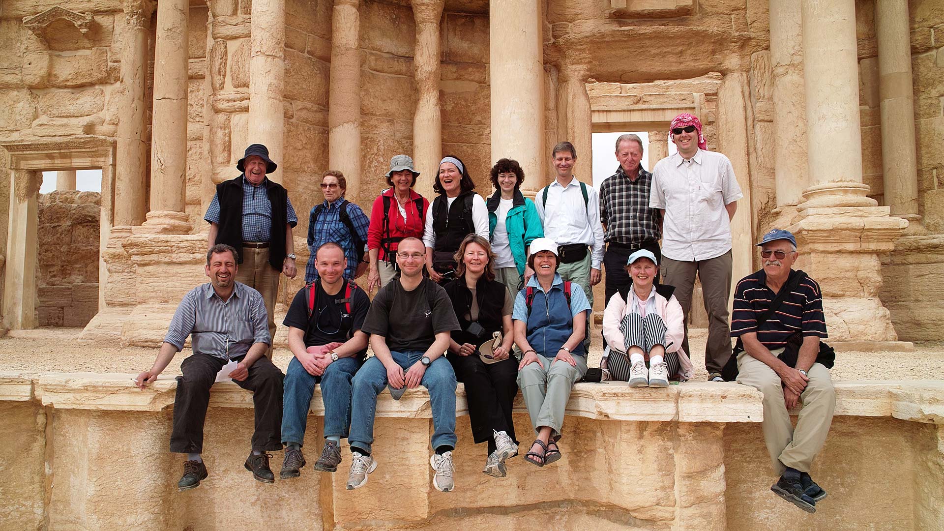 The photograph immortalizes a joyful group of tourists, their faces beaming with happiness, after their visit to Palmyra, the timeless gem that graces the land of Syria.