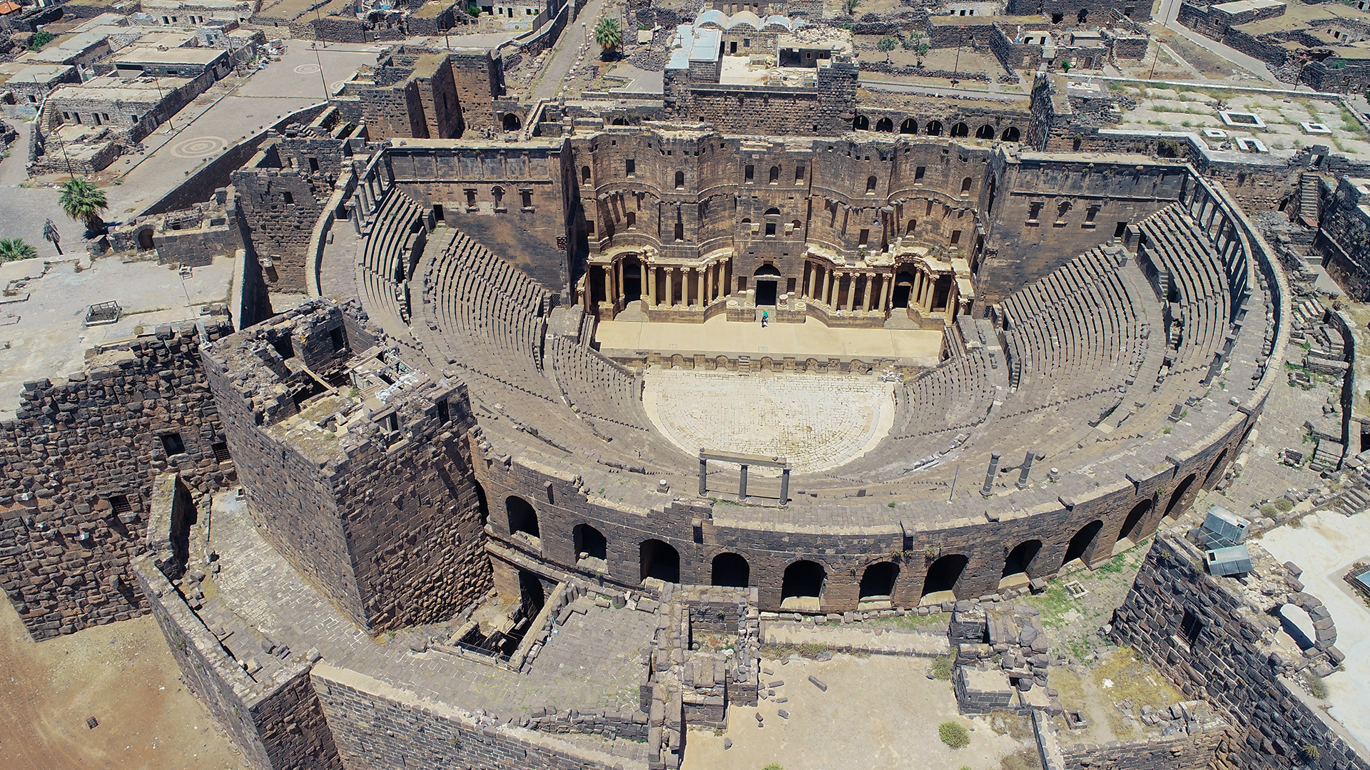An aerial photograph skillfully captures the awe-inspiring sight of the renowned and exceptionally well-preserved Roman theatre of Bosra.