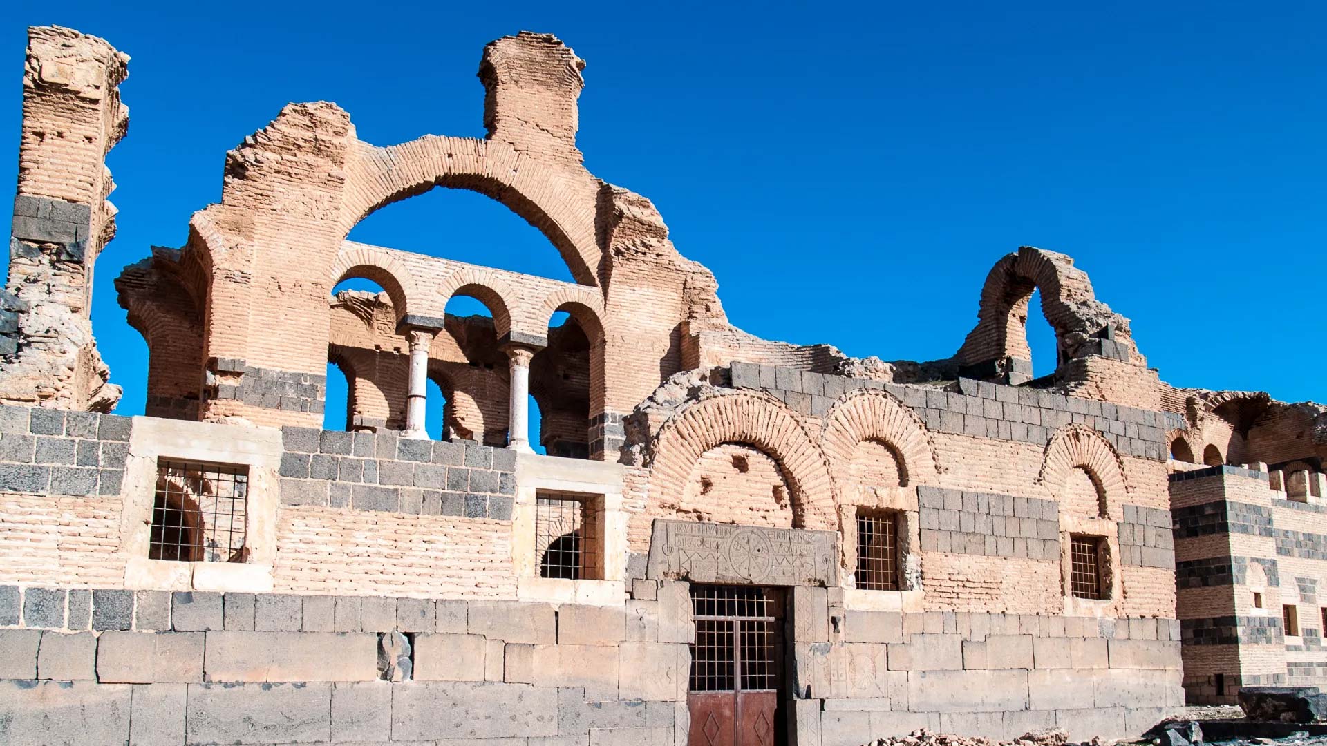 A photograph captures the impressive stone facade of Qasr Ibn Wardan, a remarkable architectural marvel that serves as a testament to the defensive prowess and grandeur of the Byzantine Empire.