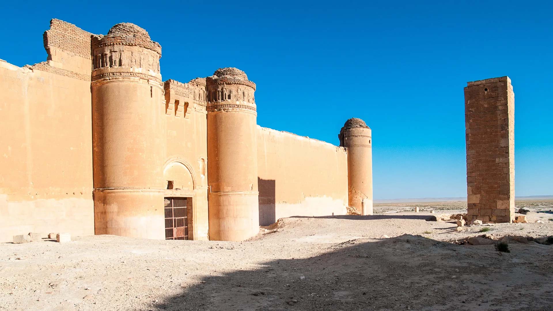 A photograph captures the imposing façade of Qasr Al Heir Al Sharqi, a castle situated in the heart of the expansive Syrian Desert, holding profound historical significance.