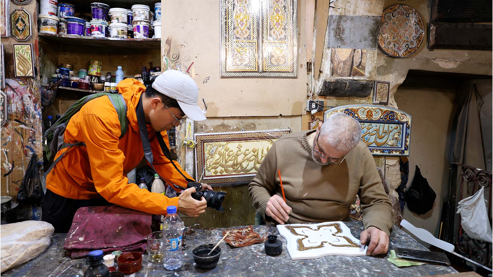A tourist is capturing photographs of a skilled craftsman from Syria, showcasing the profound Handicraft Heritage of Syria.