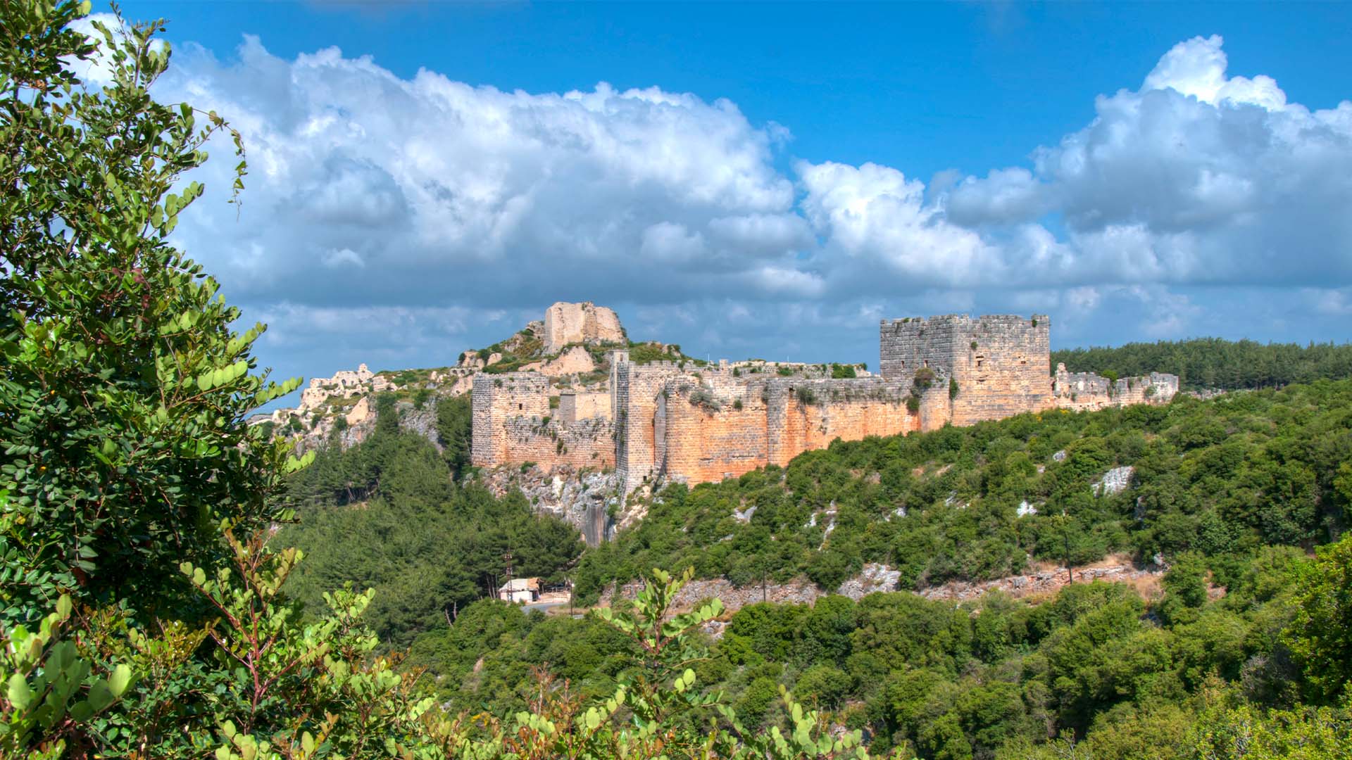 In this panoramic photograph, the historic fortress of Saladin Castle is captured, perched atop a strategic hilltop. It provides sweeping vistas of the surrounding landscape, including breathtaking views of the Mediterranean Sea.