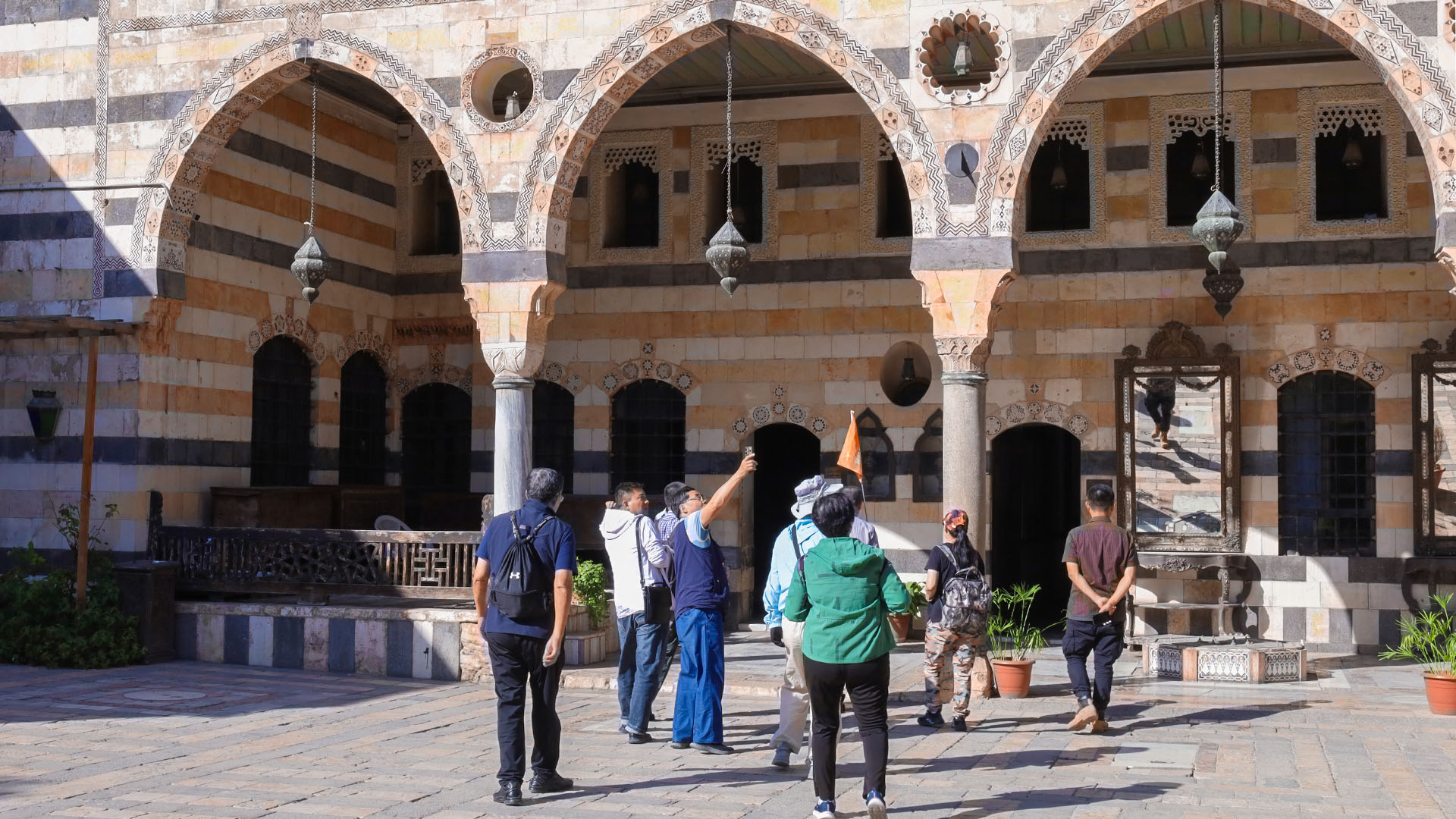 American Tourists are attentively listening to their Syrian guide in the courtyard of Damascus Azem Palace.