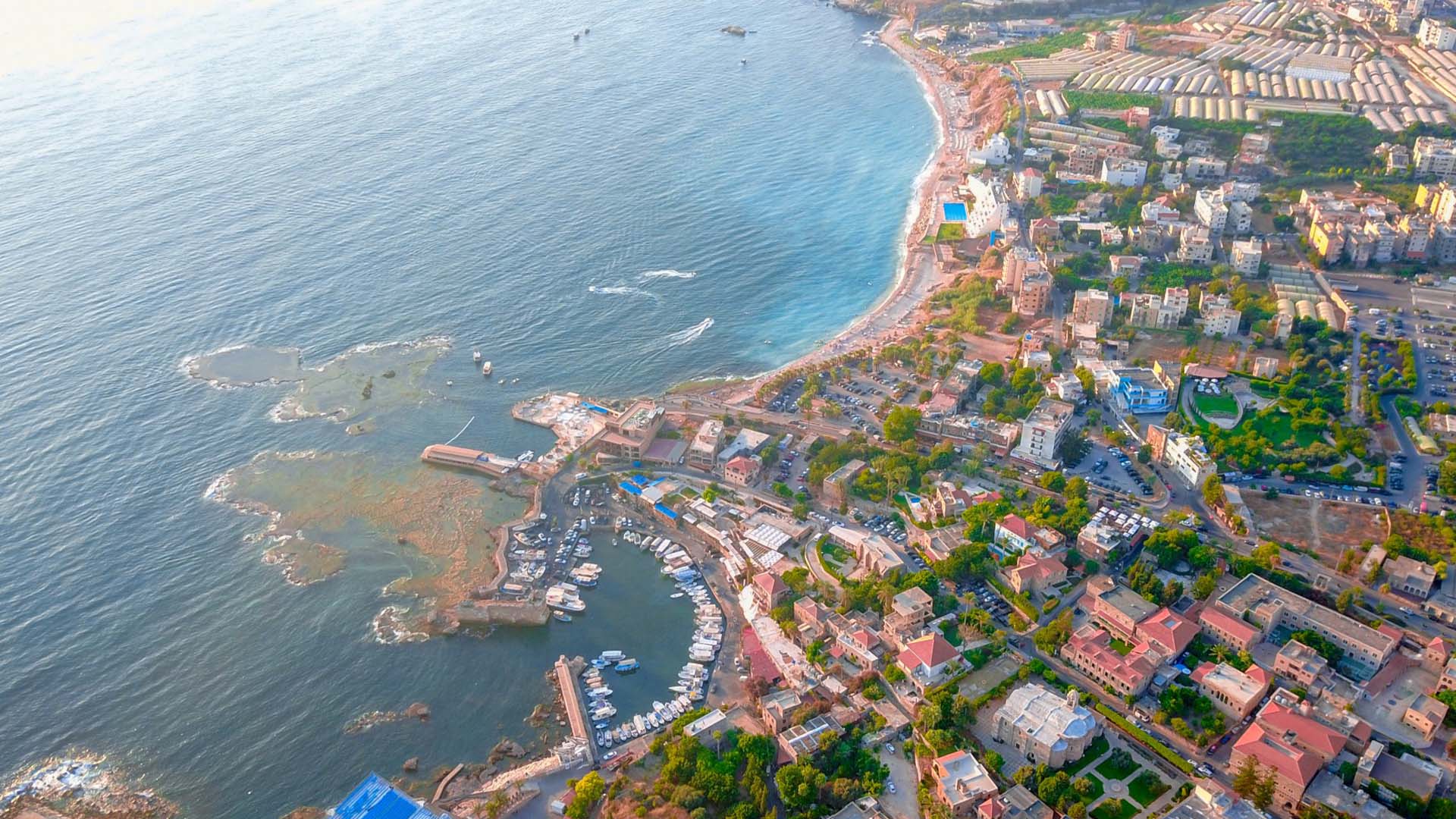 Travel to Lebanon: From an aerial perspective, a photograph unveils the enchanting city of Byblos, seamlessly blending with the shimmering waters of the Mediterranean Sea.