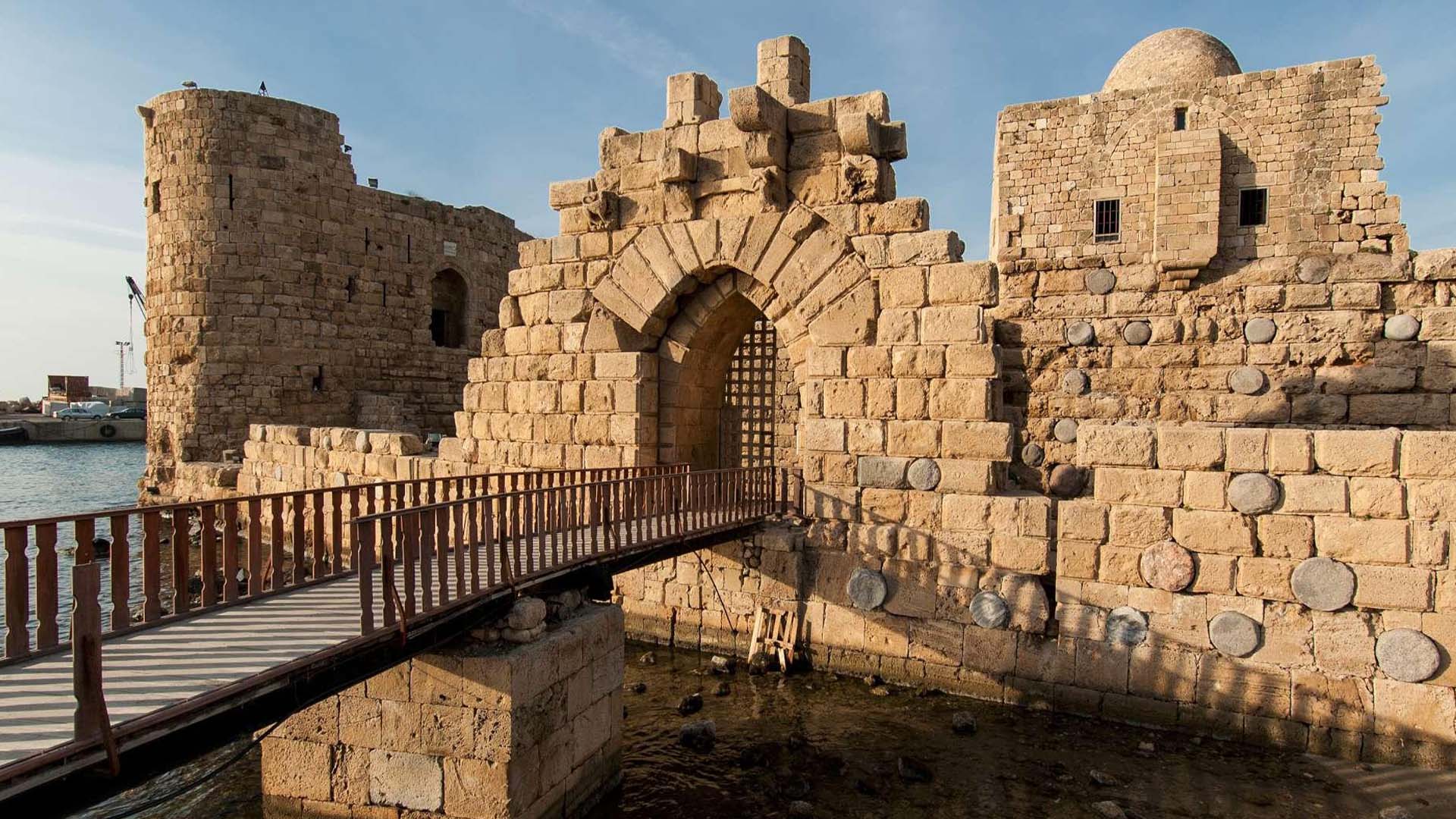 A photograph immortalizes the Sea Castle of Sidon, situated on a petite island amidst the vast expanse of the Mediterranean Sea, connected to the mainland by a slender causeway.