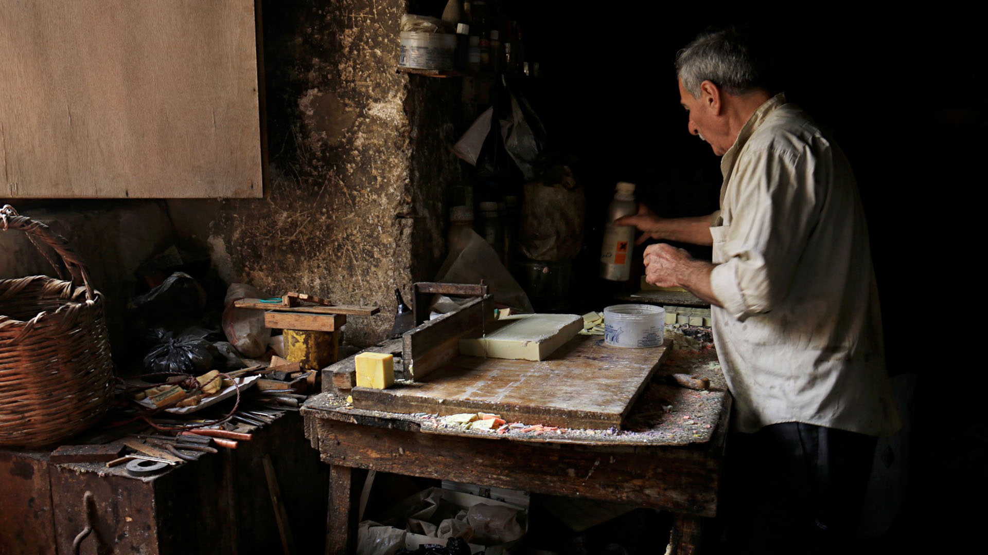 Photographs capture the expertise of a skilled craftsman from Aleppo as he carefully cuts a soap bar with precision.