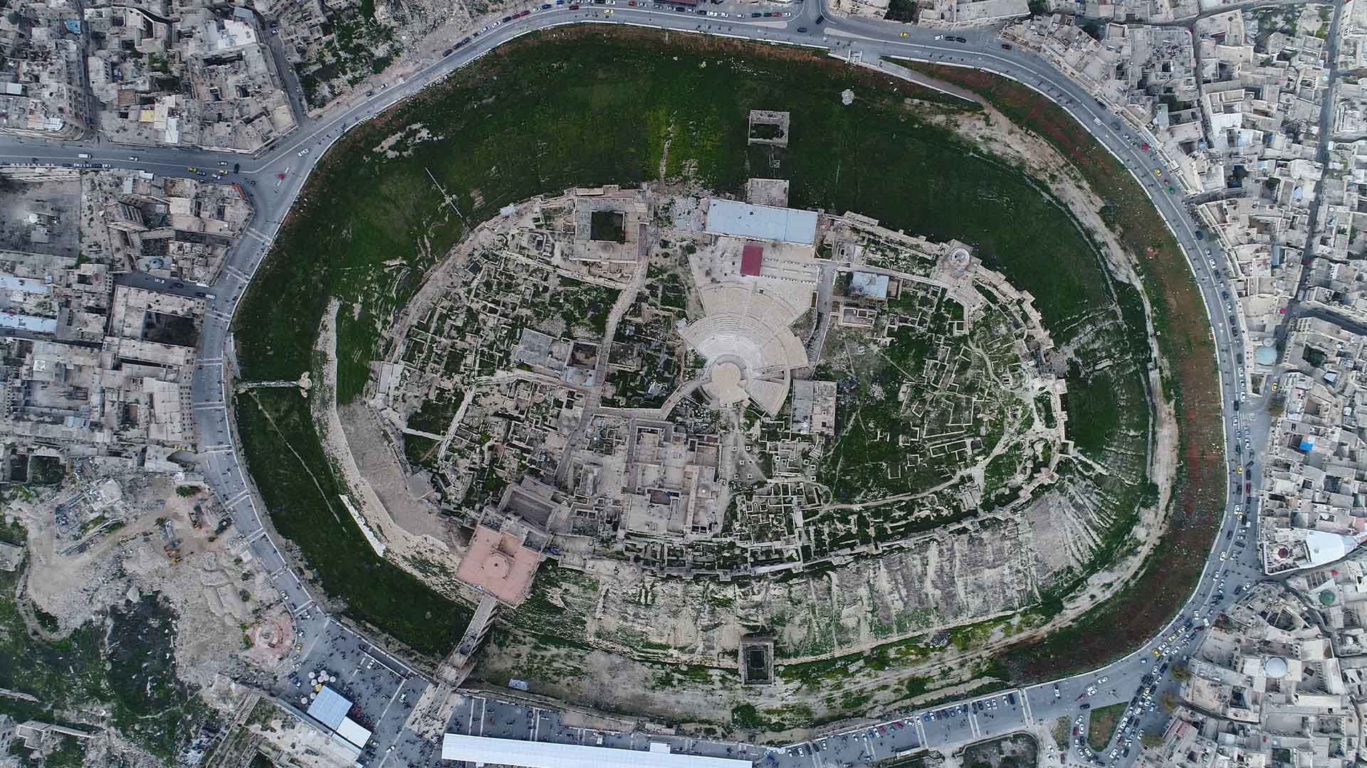 The aerial photograph captures a captivating view of the iconic Citadel of Aleppo, which holds a commanding position atop a hill in the heart of the city.