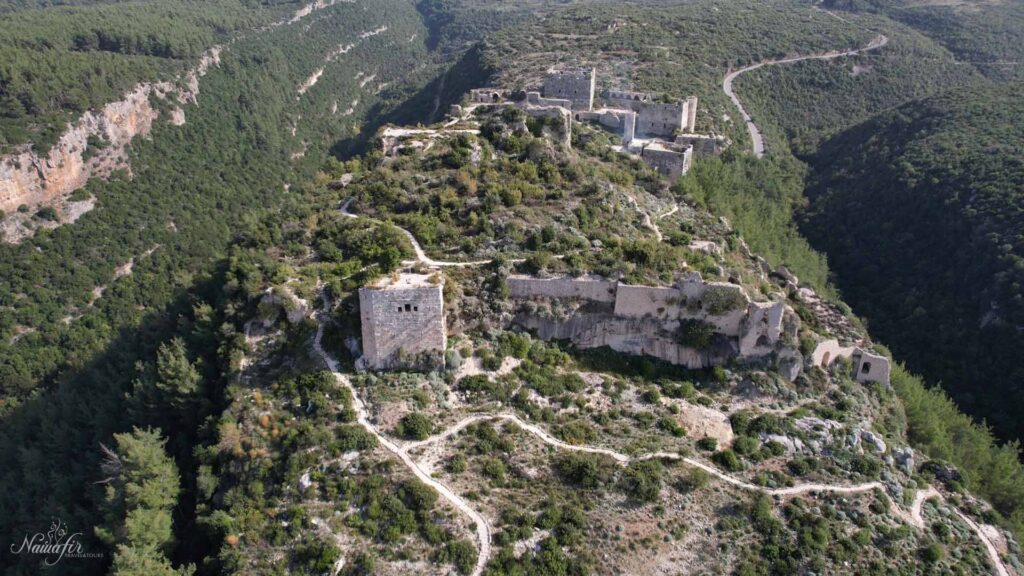 The aerial photograph offers a captivating view of the majestic Saladin Castle, celebrated for its historical and archaeological importance, nestled amidst verdant mountains that enhance its allure.