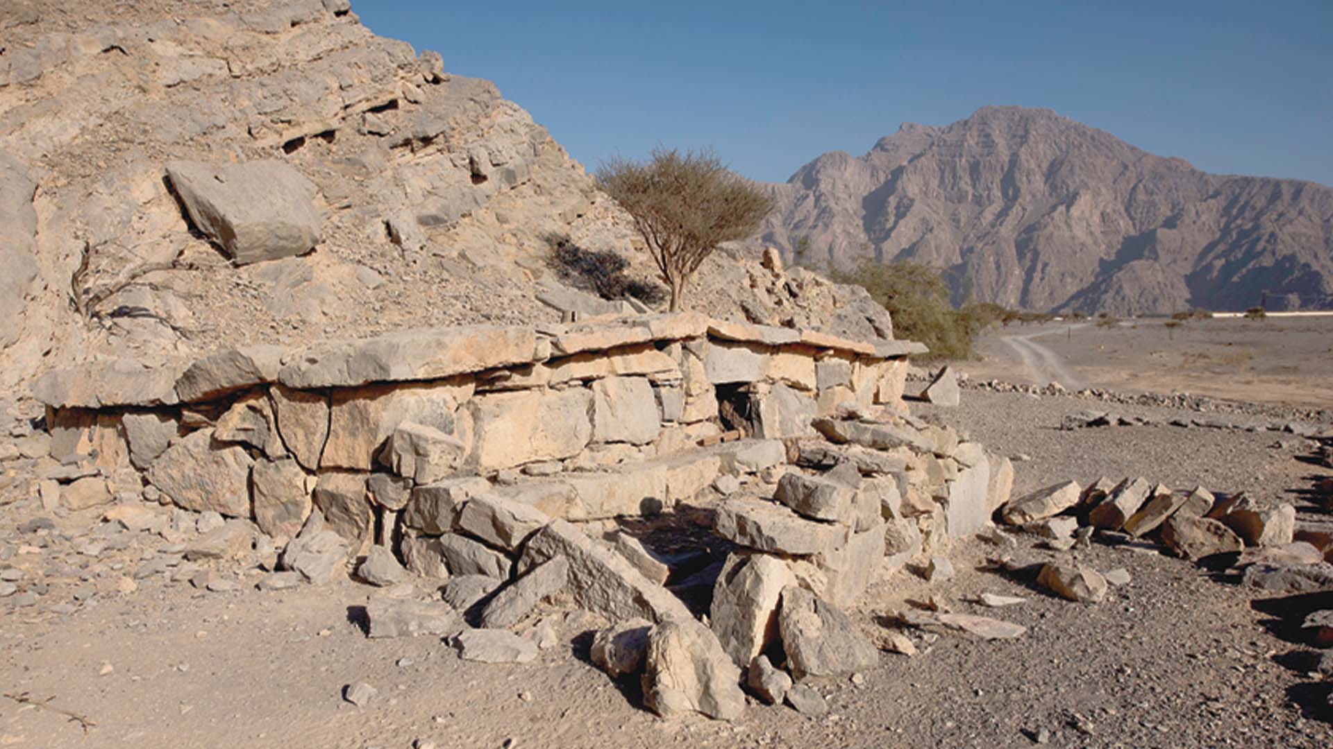 A panoramic photograph immortalizes Bait Al-Qufl, a distinctive traditional storage structure found in the Musandam Peninsula, harmoniously nestled amidst the backdrop of majestic mountains.