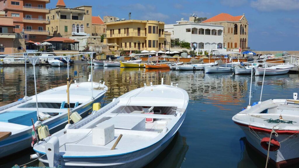 A photograph immortalizes the scenic harbor of Byblos, where boats command attention in the foreground, while charming restaurants and houses create a delightful backdrop