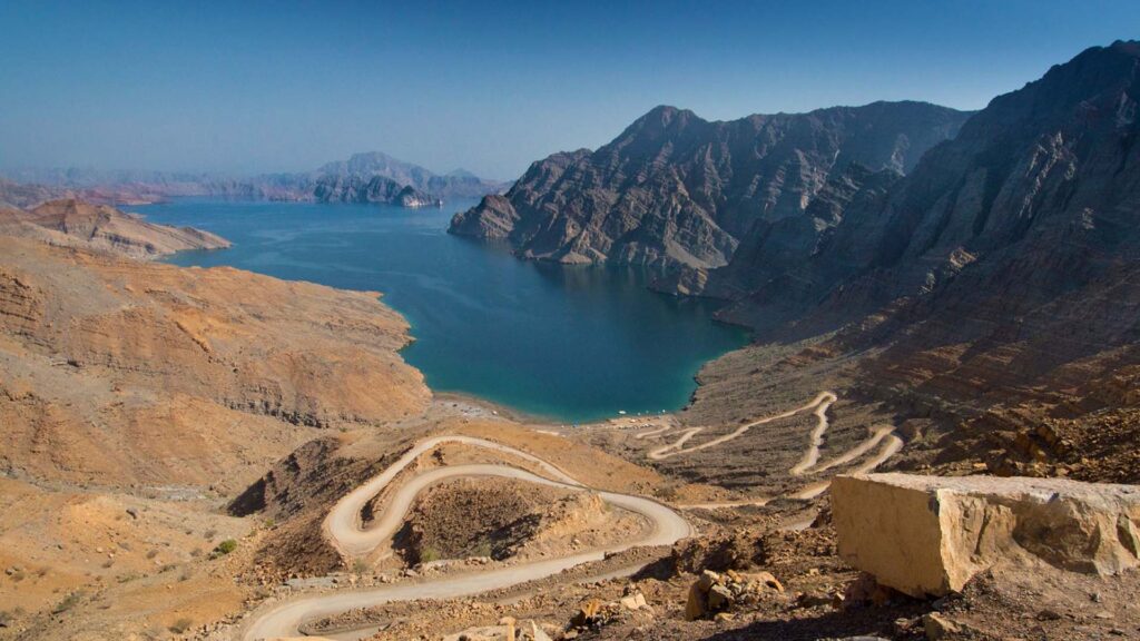 Travel to Oman: A panoramic photograph immortalizes Jebel Harim, the towering apex of the Musandam Peninsula in Oman, encircled by a majestic range of mountains, creating a breathtaking vista of natural grandeur.