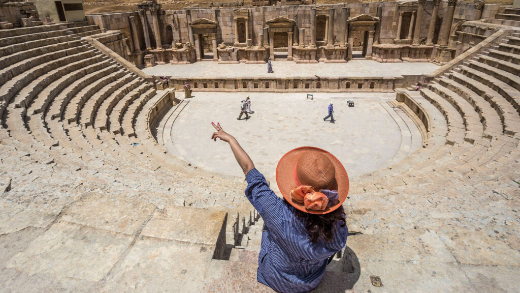 A panoramic photograph immortalizes a tourist pointing in awe at the captivating Theater of Jerash.
