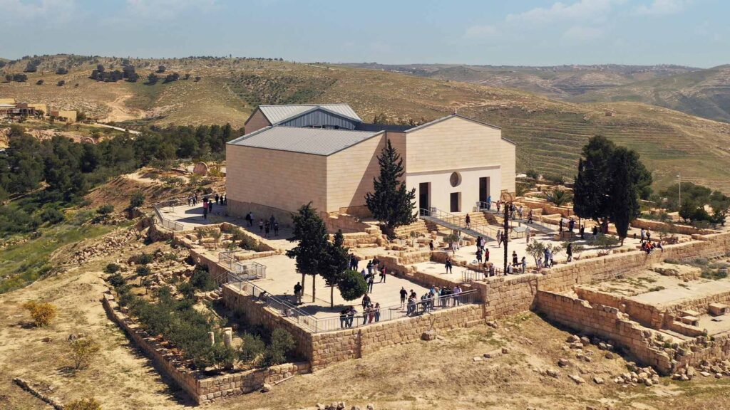 A photograph captures the timeless presence of St. George's Church in Mount Nebo, with visitors congregating in the outer courtyard.