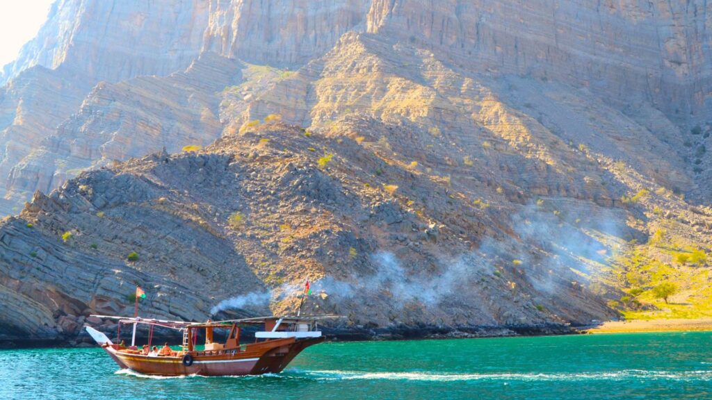 A panoramic photograph immortalizes a sailing boat gracefully navigating the waters of the Musandam Peninsula, while the majestic mountains provide a stunning backdrop.