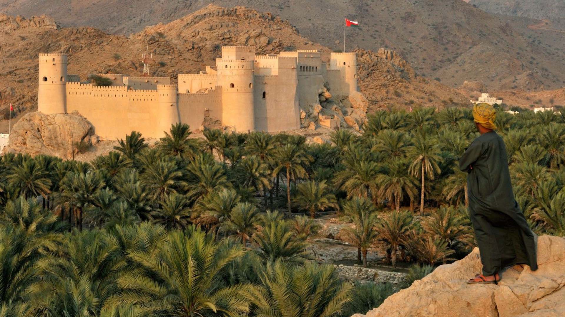 A photograph immortalizes The Nakhl Rustaq Loop with the ancient Nakhl Fort gracefully positioned atop a hill, commanding a view over lush palm groves.