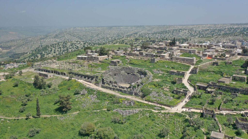 A panoramic photograph immortalizes Umm Qais, with its Roman theater taking center stage, embraced by a picturesque backdrop of lush greenery.